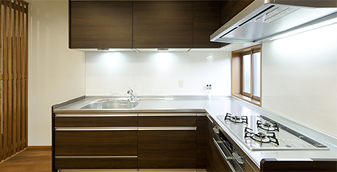 自動的に昇降する吊戸棚などの機能的な収納を設けた LIXIL のシステムキッチン。