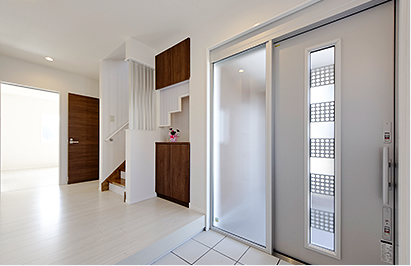 袖がFIXタイプのスライディングドア、納戸への引き戸もスクリーンタイプで玄関ホールに光を採り入れ、明るく開放感のあるエントランス空間を演出