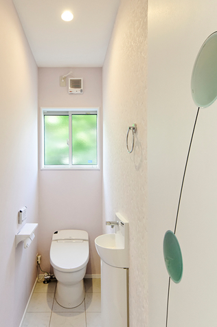 可愛らしいドアとクロスが印象的なトイレは、使い勝手のよいシステムトイレ（LIXIL サティス）で清潔感が溢れています。