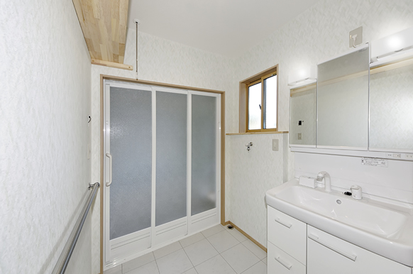 白く明るい洗面脱衣室、お風呂に隣接して洗濯機を設置。