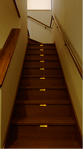 夜、ほんのり優しい灯りが足元を照らす LIXIL の木質階段。