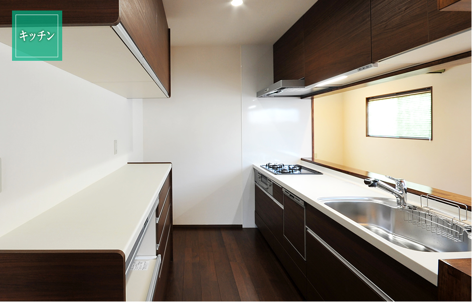 ウォールナット色の LIXIL システムキッチンに蒸気排出ユニット付の家電収納。