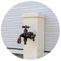 ウォールナット色のモダンな玄関横には、お洒落な立水栓（外水道）を設置。