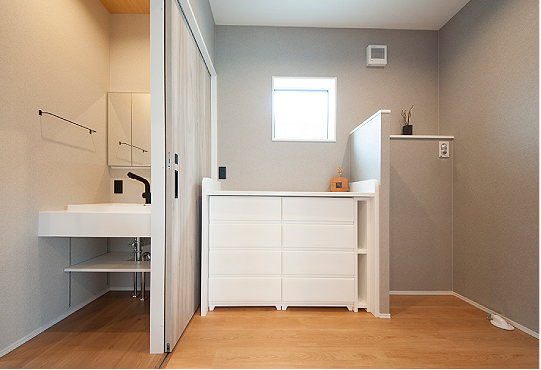 洗面台は廊下に配置し、脱衣室には洗濯機と収納ボックスの高さに合わせて造作カウンターを設置。限られた空間を有効活用できるよう、隙間収納も取り入れています。