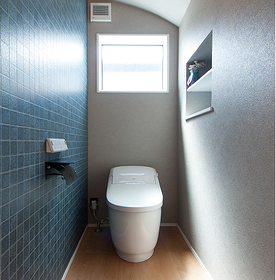 階段下のスペースを活かしたトイレは、天井をアーチ型にすることでやわらかな印象に。使い勝手を考え、収納棚も設けました。